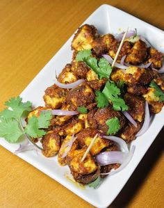 a white plate topped with meat covered in onions and cilantro