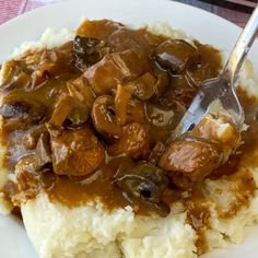 a white plate topped with mashed potatoes covered in gravy