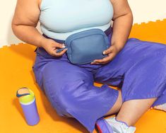 a woman is sitting on the floor with her purse and water bottle in front of her