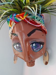 a potted plant with eyes painted on it's face and some hair hanging from the wall