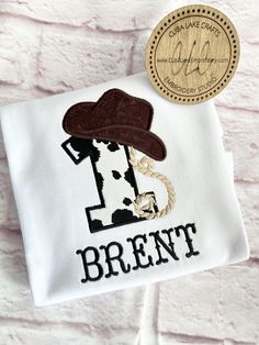 a white t - shirt with a brown hat and the words brent on it