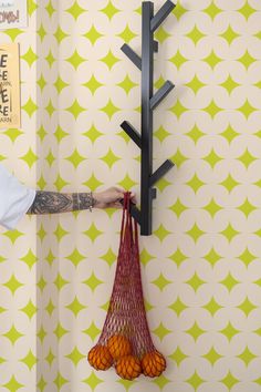 a person holding a bag with oranges hanging from it's hooks on a wall