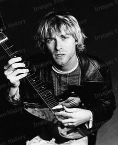 a man holding an electric guitar in his right hand and wearing a leather jacket on the left