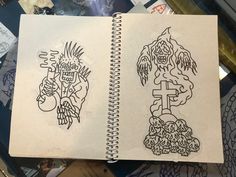 two notebooks with drawings on them sitting on a table next to papers and pens