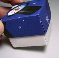 a hand holding a blue and white object with snowflakes on it's side