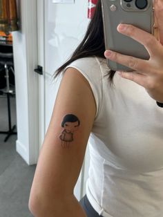 a woman with a small tattoo on her arm taking a selfie in the mirror