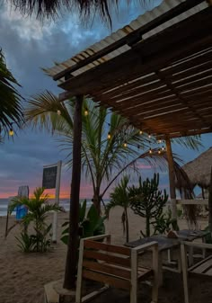 an outdoor seating area on the beach at dusk