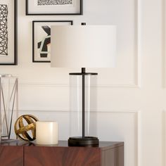 a table with a lamp and pictures on the wall