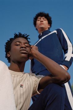 two young men sitting next to each other in front of a blue and white sky