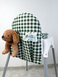 a brown dog sitting on top of a green and white checkerboard chair next to a stuffed animal