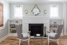 a living room with two chairs and a fire place in the middle of the room