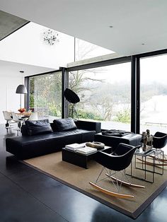 a living room filled with black furniture and large windows