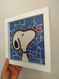 a hand holding up a framed piece of art that has been made to look like a mosaic