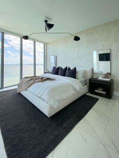 a large bed sitting in the middle of a bedroom next to a tall glass window