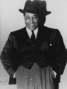 a black and white photo of a man in a suit with a hat on his head