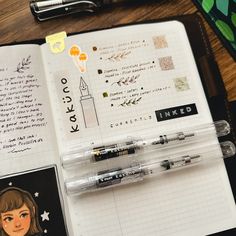 an open notebook with pens and stickers on it