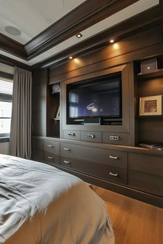 a bedroom with a bed, dressers and television on the wall in front of it