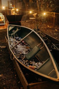 a small boat sitting on top of a field next to a pile of bottles and cans