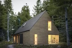 a small house in the woods with windows on each side and lights on at the top