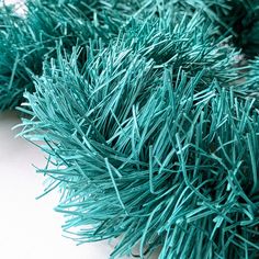 closeup of green grass on white surface with small amount of needles in the foreground