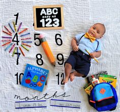 a baby doll laying on top of a blanket next to school supplies and books,