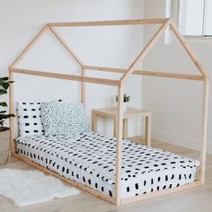 a white bed with a black and white patterned comforter on top of it next to a potted plant