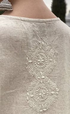 the back of a woman's shirt with an intricate embroidered design on it,