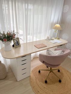 a desk with a chair, laptop and flowers on it