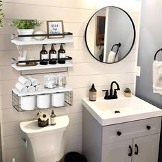 a white toilet sitting next to a sink in a bathroom under a mirror and shelves