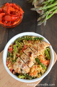 a white bowl filled with rice and vegetables next to a wooden cutting board on top of a table