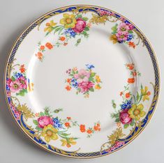 a white plate with colorful flowers and blue trimmings on the rim, against a gray background