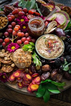 a platter filled with fruit, nuts and dip