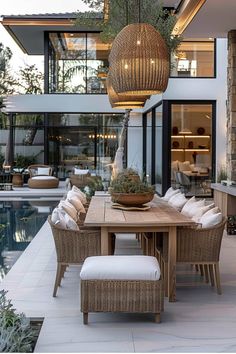 an outdoor dining area with chairs and a table next to a swimming pool in front of a house