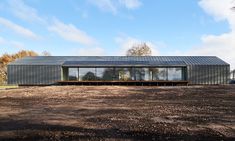 a large metal building sitting on top of a dirt field next to a lush green forest