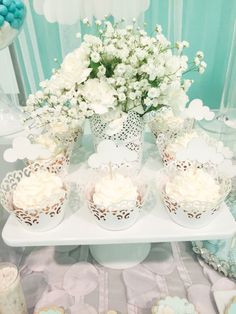 some cupcakes are sitting on a table with white flowers in vases next to them