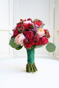 a bouquet of red and pink flowers sitting on top of a table