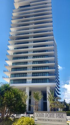 a tall white building sitting next to palm trees