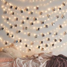 a bedroom with lights strung from the ceiling and pictures hanging on the wall above it