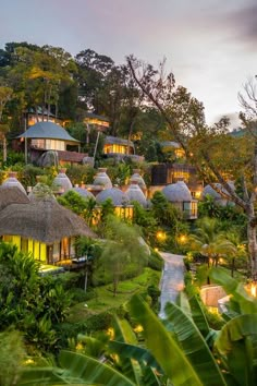 the resort is surrounded by lush vegetation and lit up lights at night, with thatched roofs