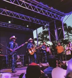 a group of people standing on top of a stage next to each other with guitars