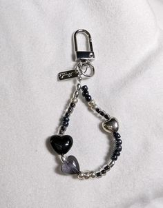 a black and white beaded bracelet with heart charms on it's end, hanging from a metal hook