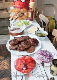 a table topped with lots of food on top of a white wooden table next to chairs