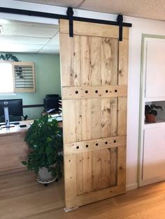 an open wooden door sitting in the middle of a room next to a computer desk