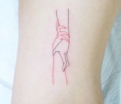 a small tattoo on the back of a woman's lower leg, with a line drawing of a hand holding a string