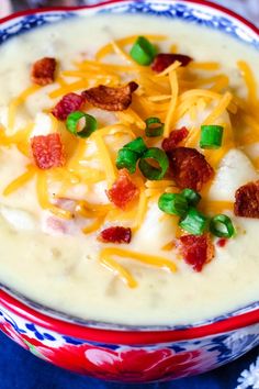 a bowl of potato soup with bacon, cheese and green onions in it on a blue table cloth