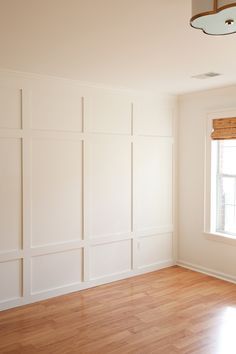 empty room with hard wood flooring and white paint on the walls in front of a window