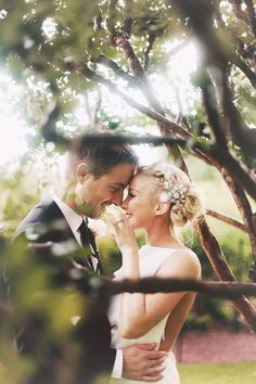 a man and woman standing next to each other in front of trees with the caption pin it