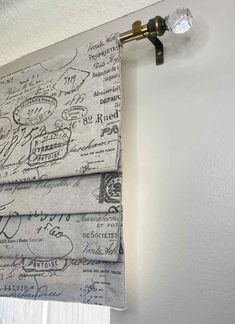 a curtain hanging on the side of a white wall with writing and drawings drawn on it