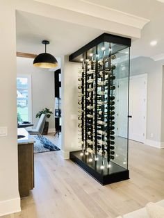 a wine cellar in the middle of a living room with wood floors and white walls