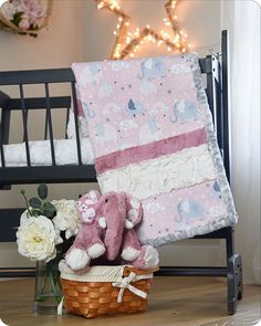 a teddy bear sitting on top of a basket next to a baby blanket and flowers